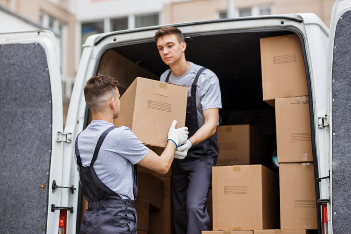 Two workers packing same-size boxes into a truck.